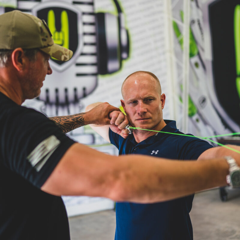 John Dudley showing Leif Babin how to use an archery shot trainer to improve his archery technique.