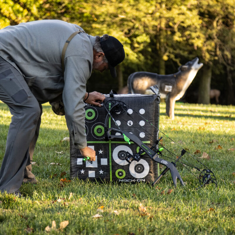 John Dudley pulling arrows from a target while shooting archery in the wind.