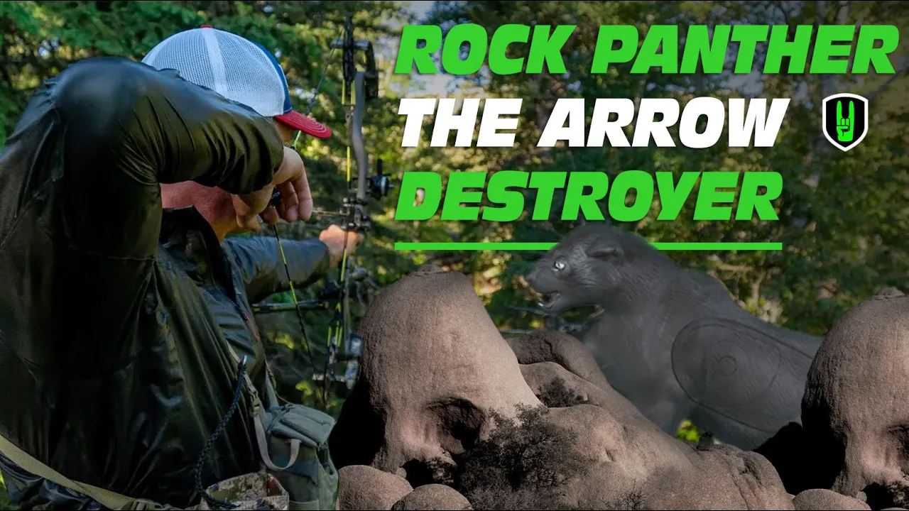 ROCK PANTHERS - A Disaster Waiting To Happen! 1 John Dudley aiming a compound bow at a 3D panther target positioned on rocks, with the text ‘ROCK PANTHER THE ARROW DESTROYER’ overlaid in bold green and white letters.