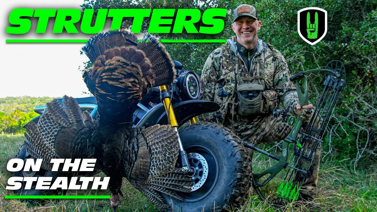 STRUTTERS IN STEALTH MODE - BOWHUNTING GOBBLERS 1 John Dudley smiling next to a harvested wild turkey, which is propped up against an off-road vehicle, with his compound bow in hand, in a grassy outdoor setting.