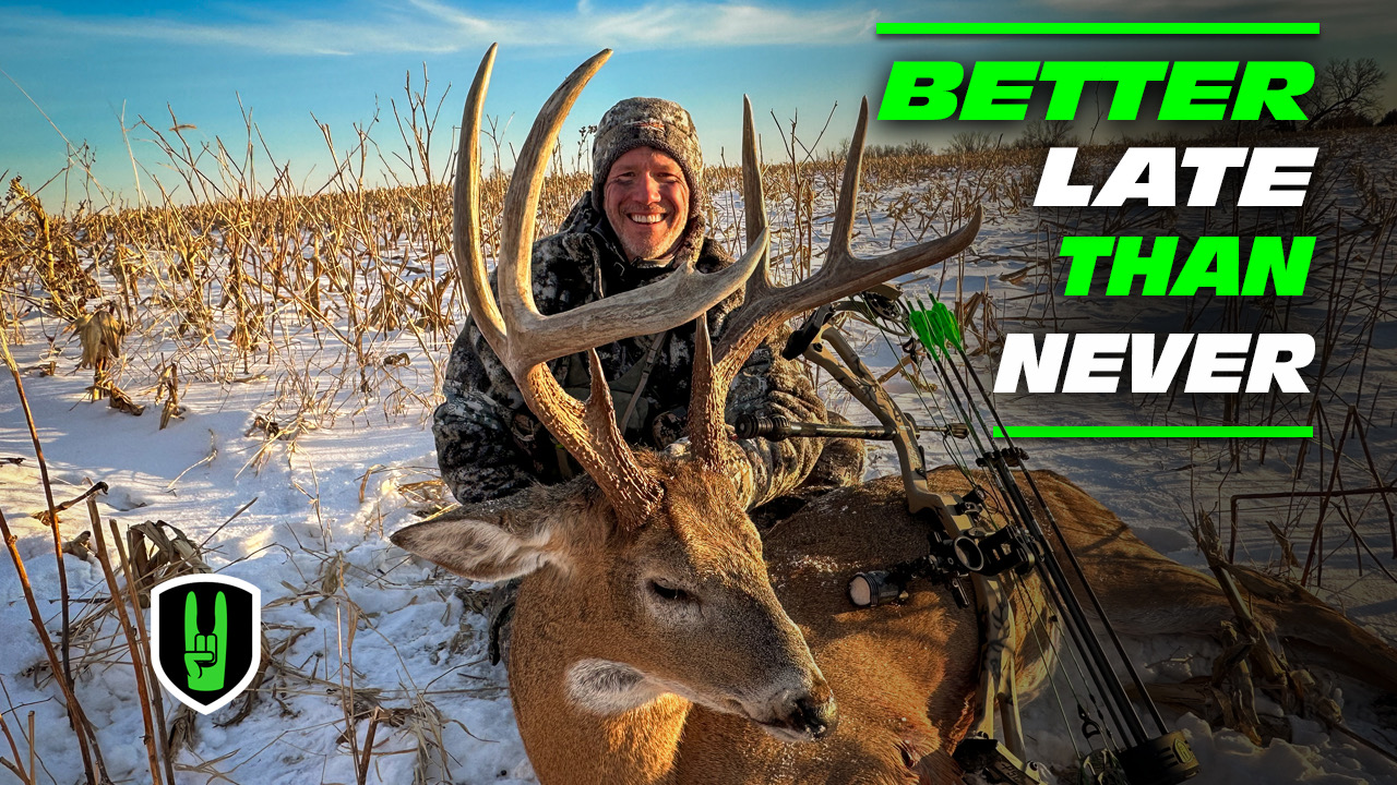 BETTER LATE THAN NEVER - LATE SEASON STUD WHITETAIL 1 John Dudley smiling while posing with a harvested whitetail deer in a snowy field, with the text ‘BETTER LATE THAN NEVER’ in bold green and white letters overlaid on the image. The Nock On Archery logo is also visible in the bottom left corner.
