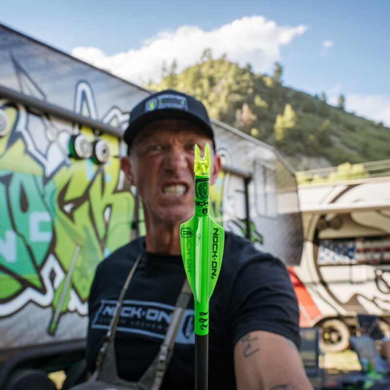 John Dudley snarling and holding up a custom Nock On arrow.