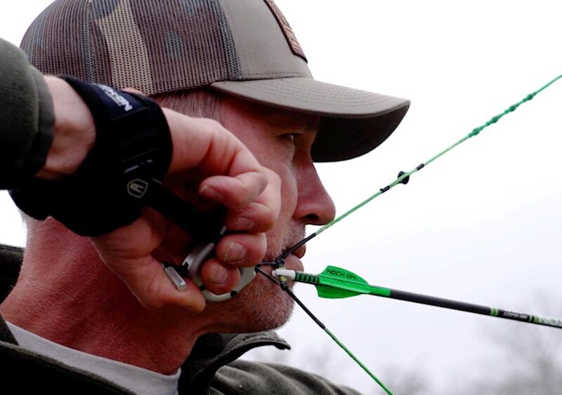 John demonstrates proper archery form, inhaling through his nose before pausing his breath at full draw.
