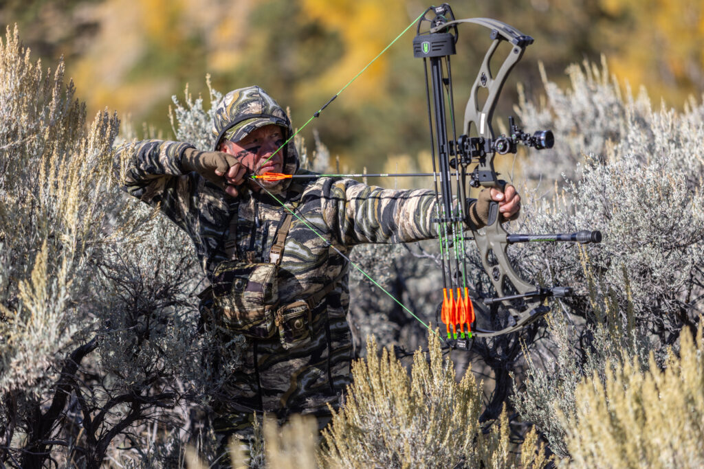 John stands. holding the new Hoyt RX-9 Ultra Bow, wearing full camouflage.