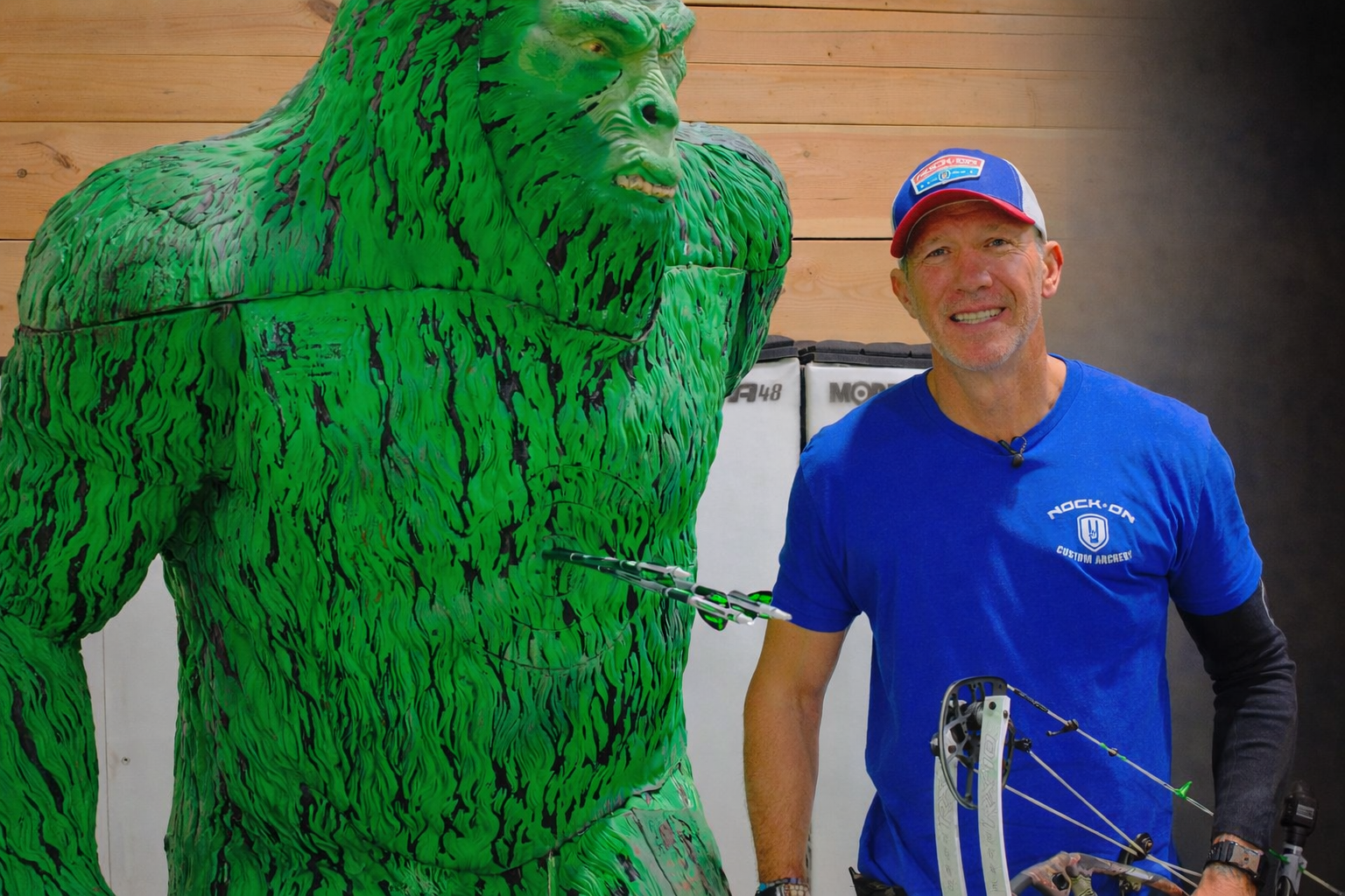 A man in a blue Nock On Custom Archery shirt and trucker cap.